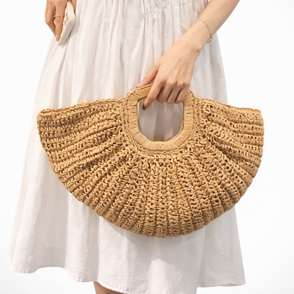 Person holding a woven beige handbag against a white background
